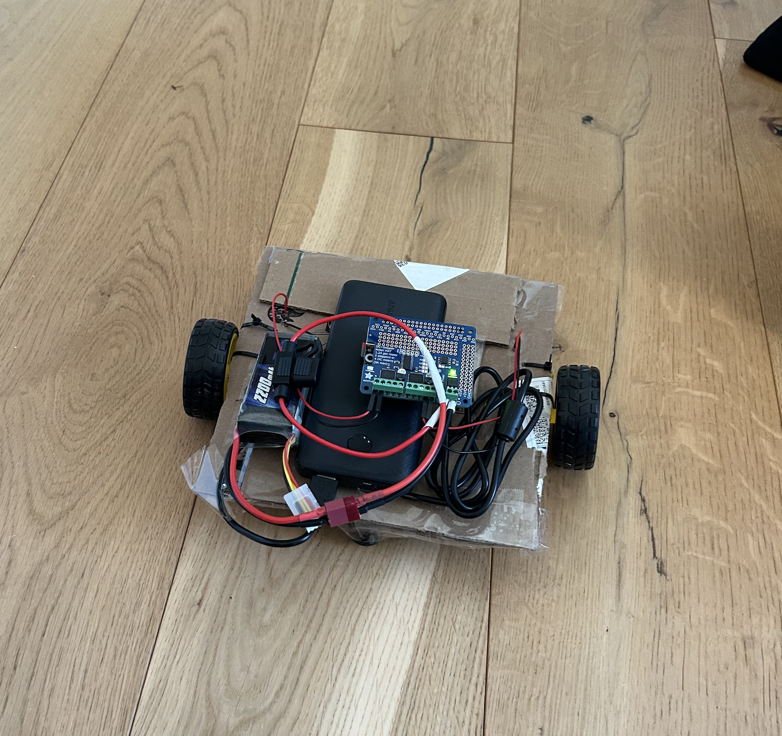 Robot vacuum prototype with wheels, motors, and electronics on a cardboard chassis